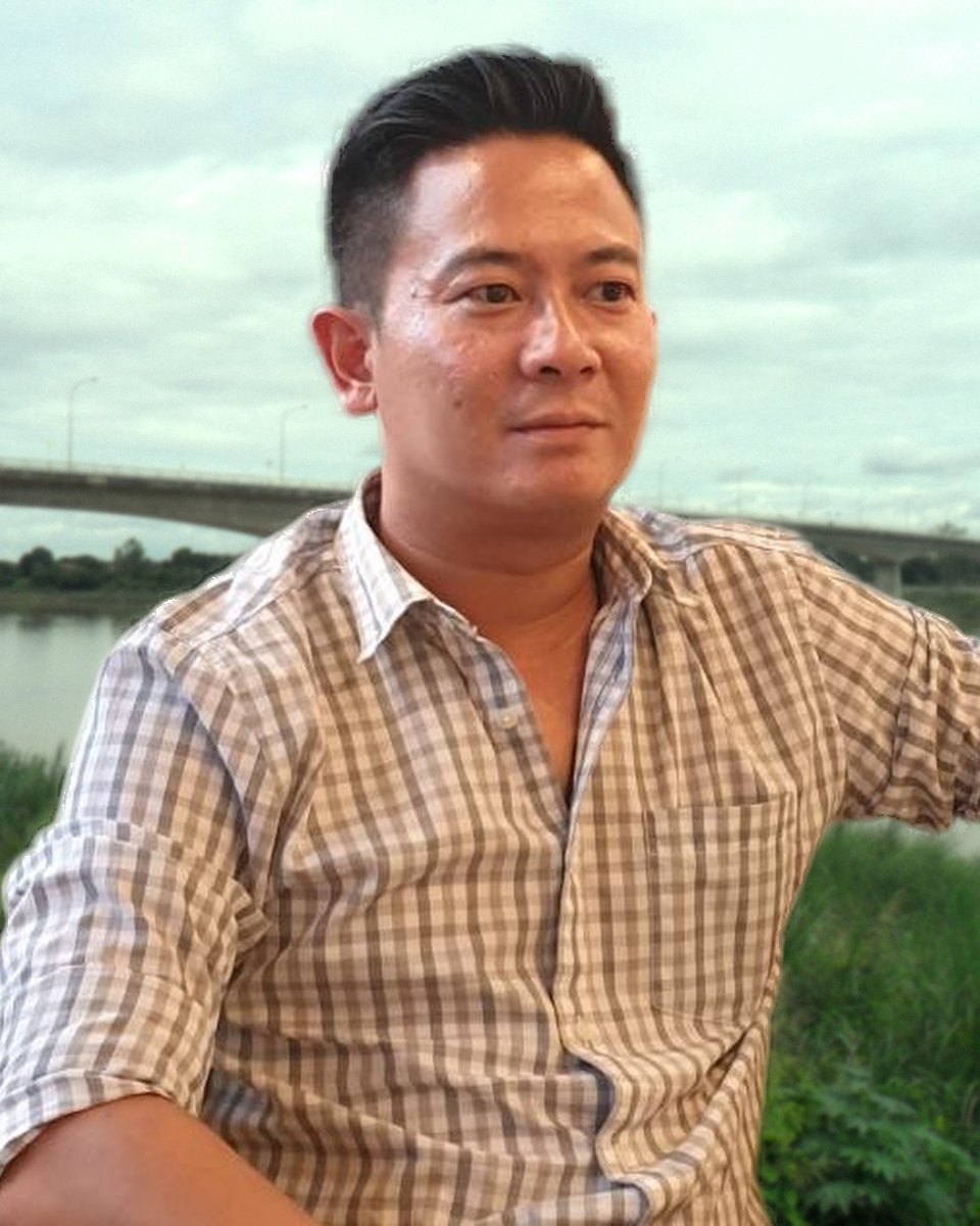 Atjawin (Up) in a gray checked shirt, with the Thai-Lao Friendship Bridge over the Mekong in Nong Khai behind him